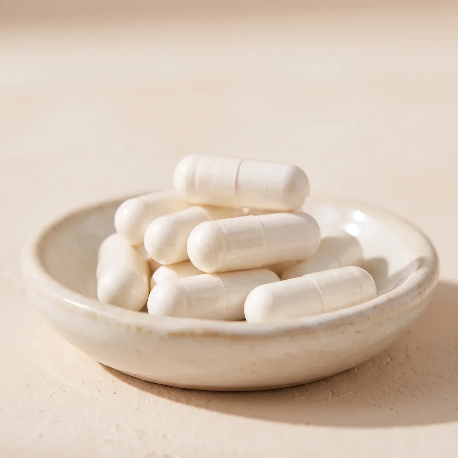 Capsules in a small dish beside a glass of water